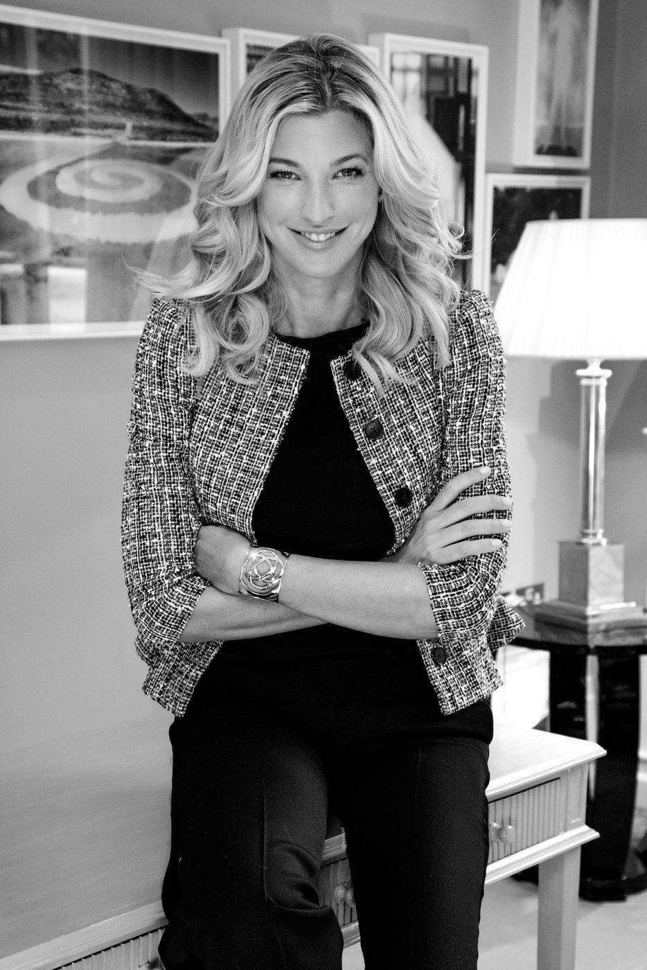 Black and white portrait of Nicole Junkermann smiling in a patterned jacket in a softly lit room