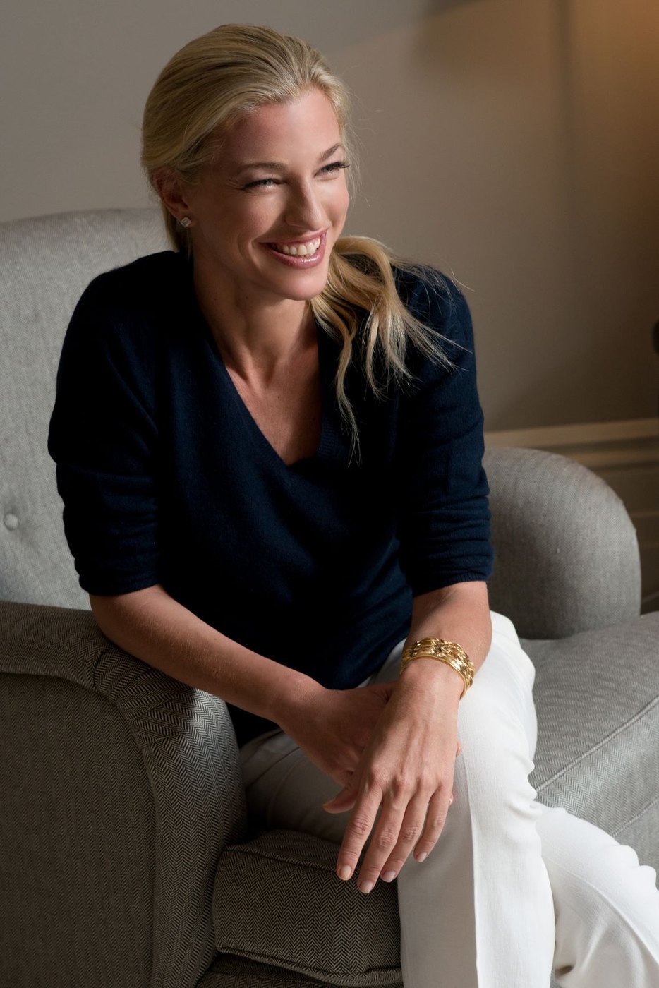 Nicole Junkermann in a navy jumper, seated in a softly lit room, smiling as she looks away from the camera